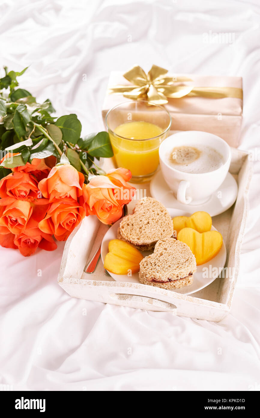 La prima colazione e le rose di colore giallo sul lenzuolo bianco per il giorno di San Valentino. Spazio di copia Foto Stock