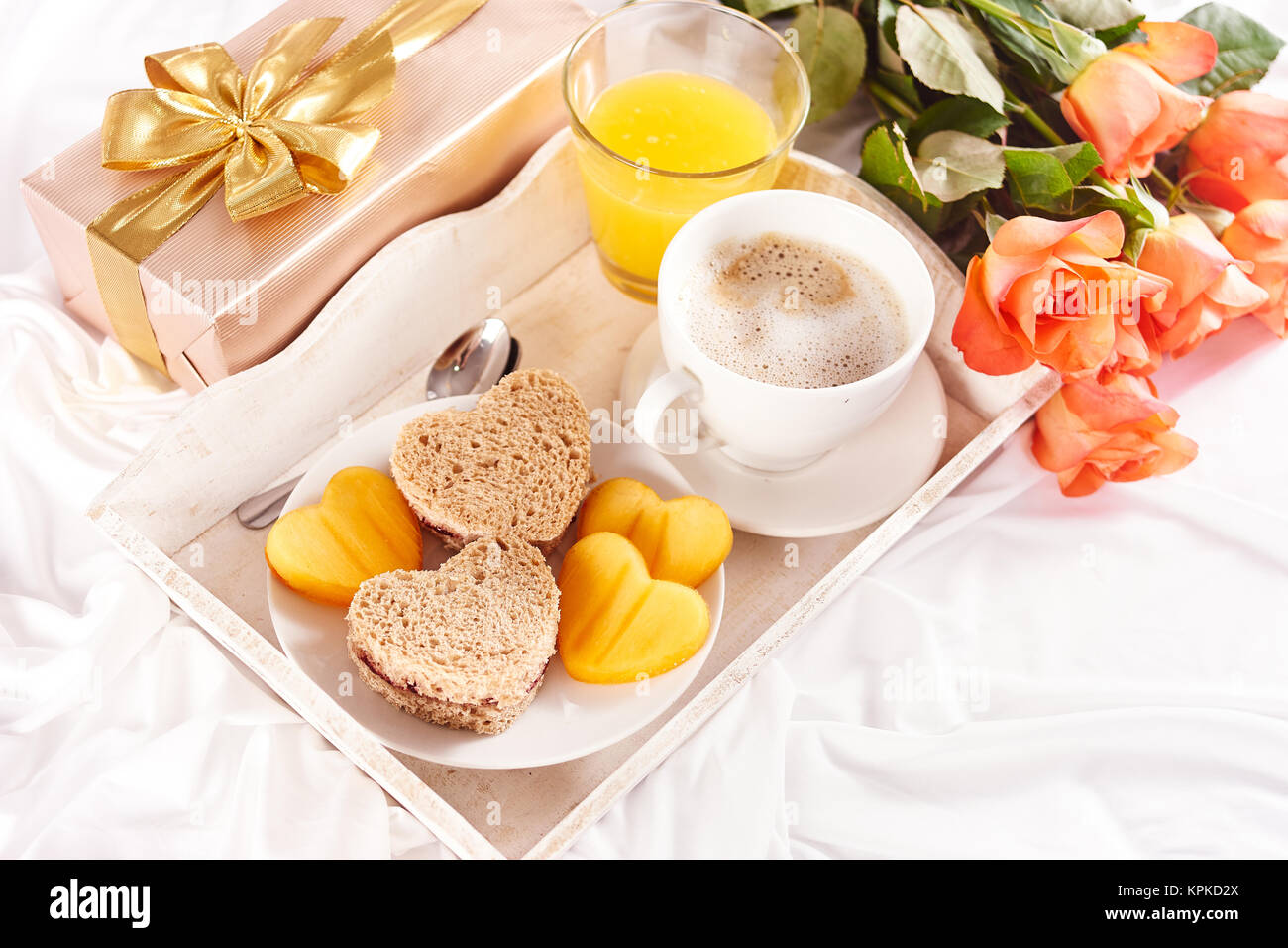 La prima colazione e orange rose sul lenzuolo bianco per il giorno di San Valentino Foto Stock