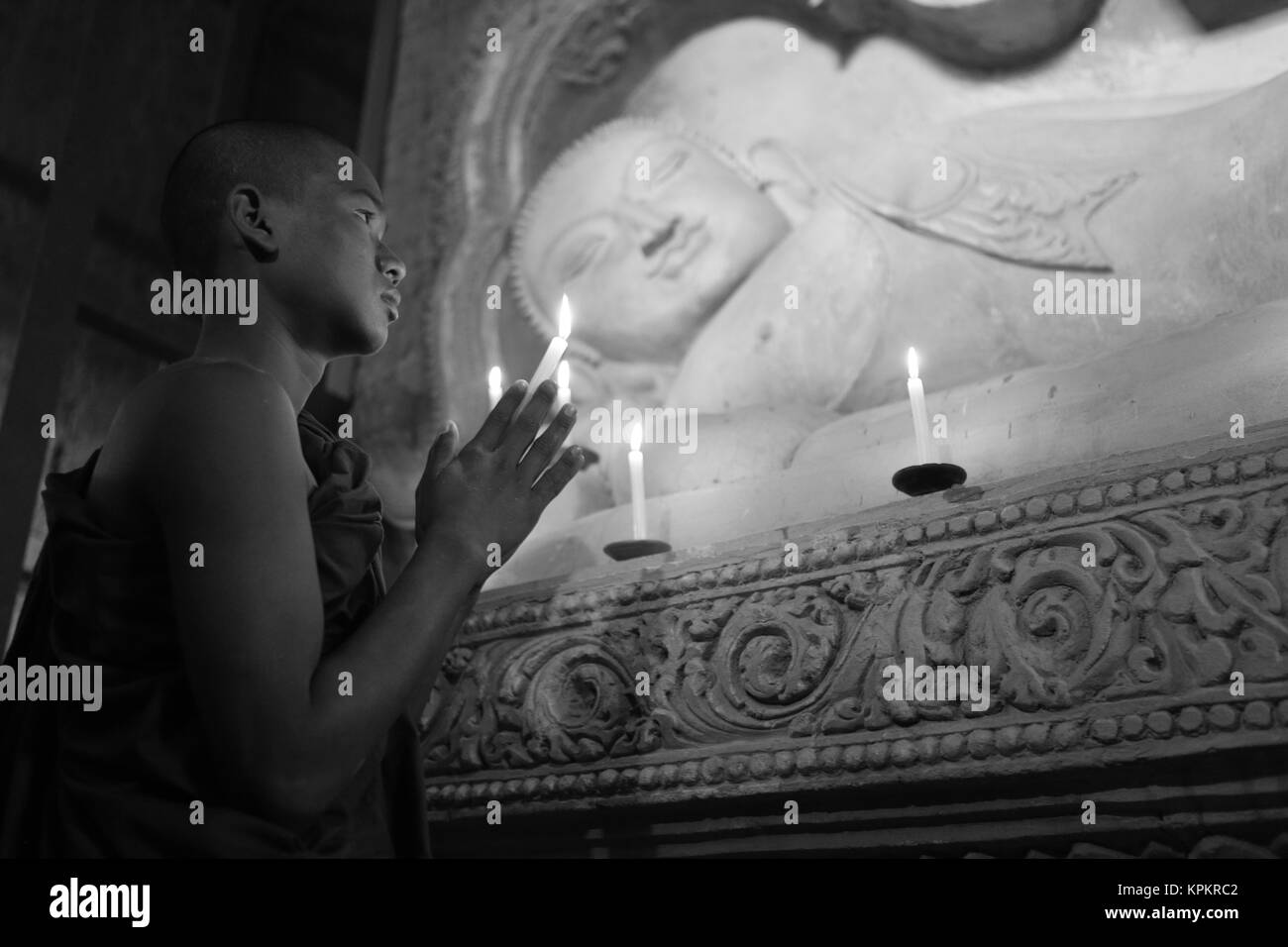 Monaco buddista in preghiera a lume di candela Foto Stock
