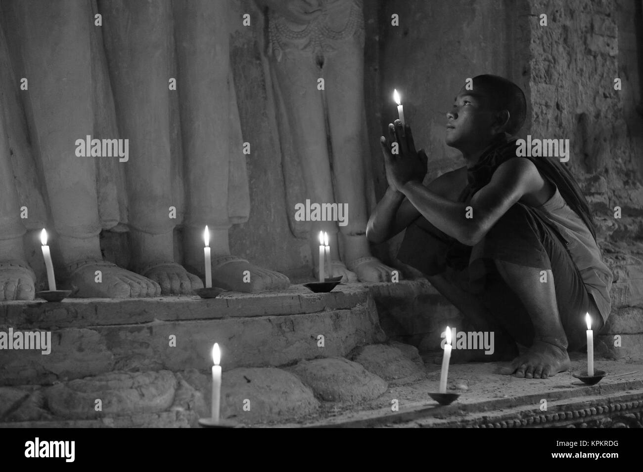 Monaco buddista in preghiera a lume di candela Foto Stock