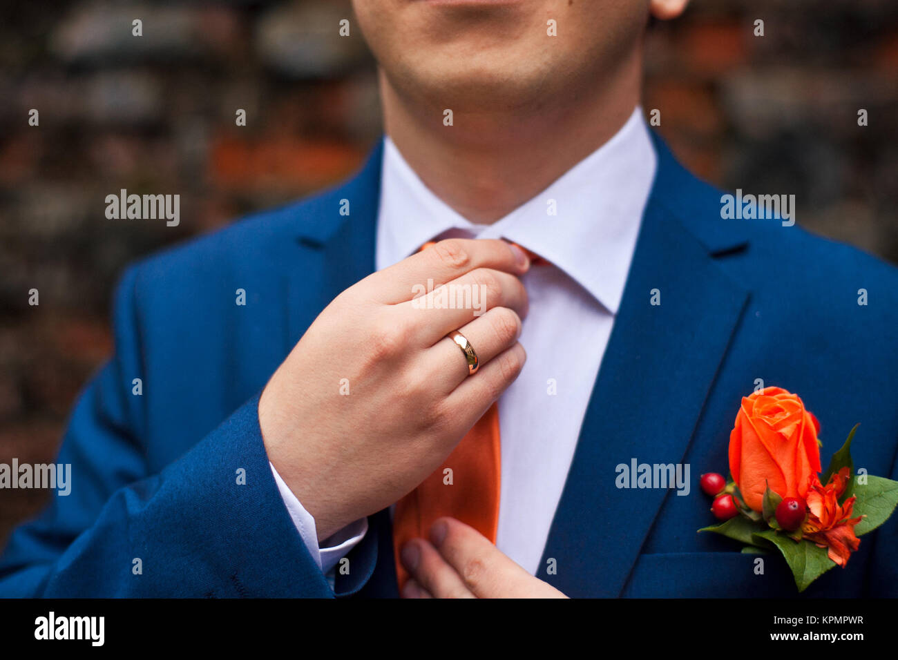 Lo sposo in una tuta blu regola la sua cravatta arancione Foto stock - Alamy