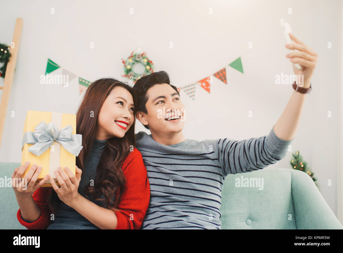 Natale coppia asiatica. Un uomo bello dando la sua fidanzata/moglie un regalo a casa per celebrare il nuovo anno persone Foto Stock