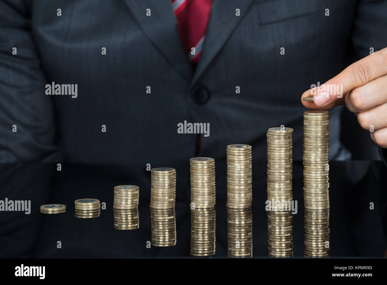 Close-up di imprenditore mano messo monete sulla pila di monete Foto Stock