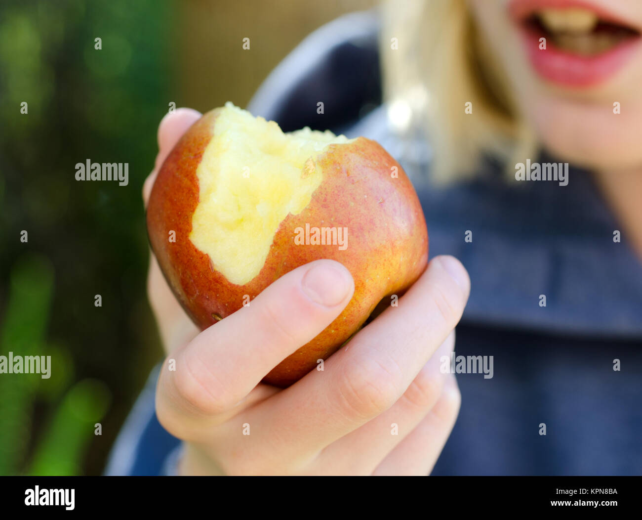 Un bambino di mangiare un Apple al di fuori in giardino. Foto Stock