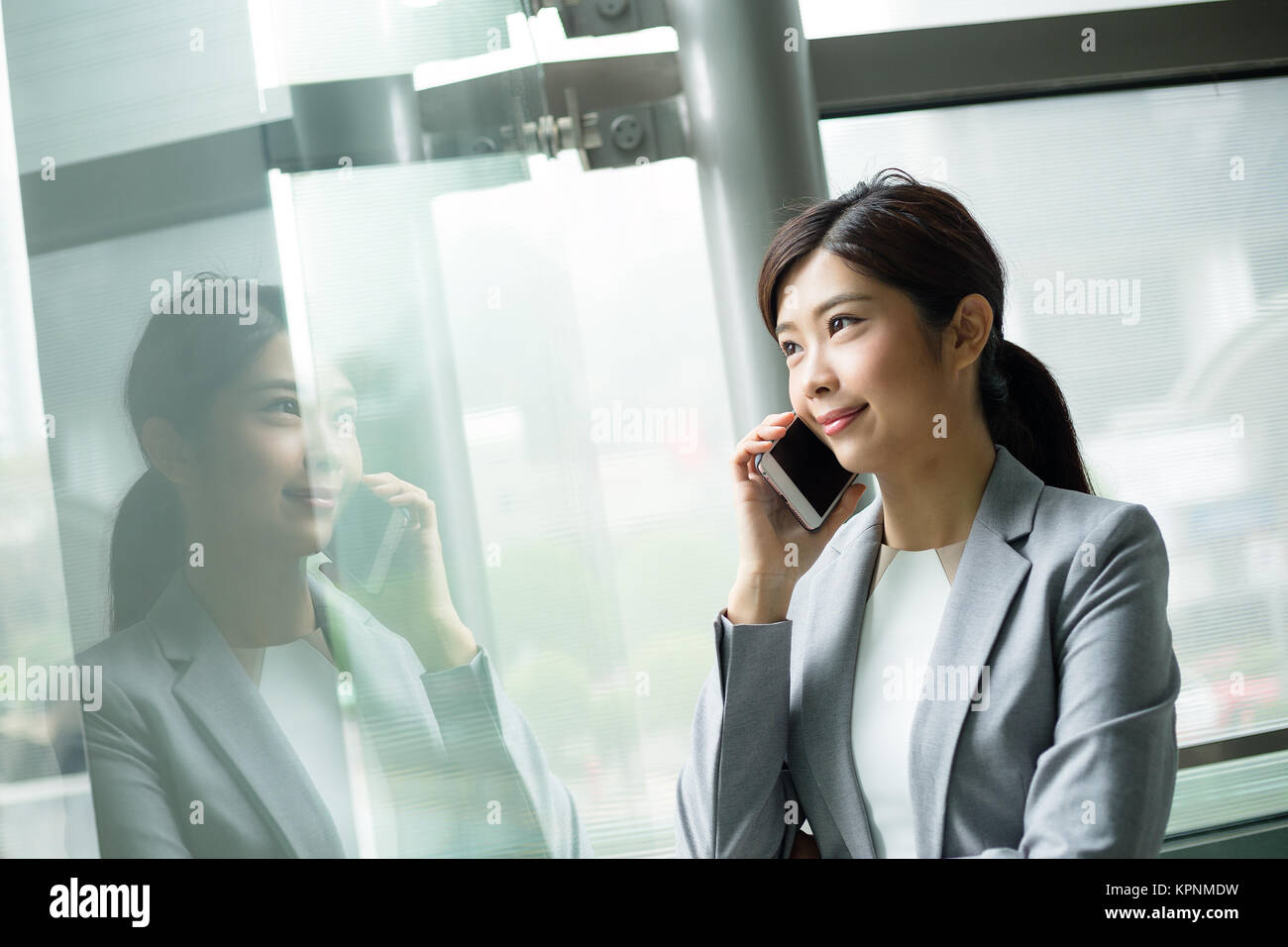 Imprenditrice parlare al cellulare all'interno di office Foto Stock