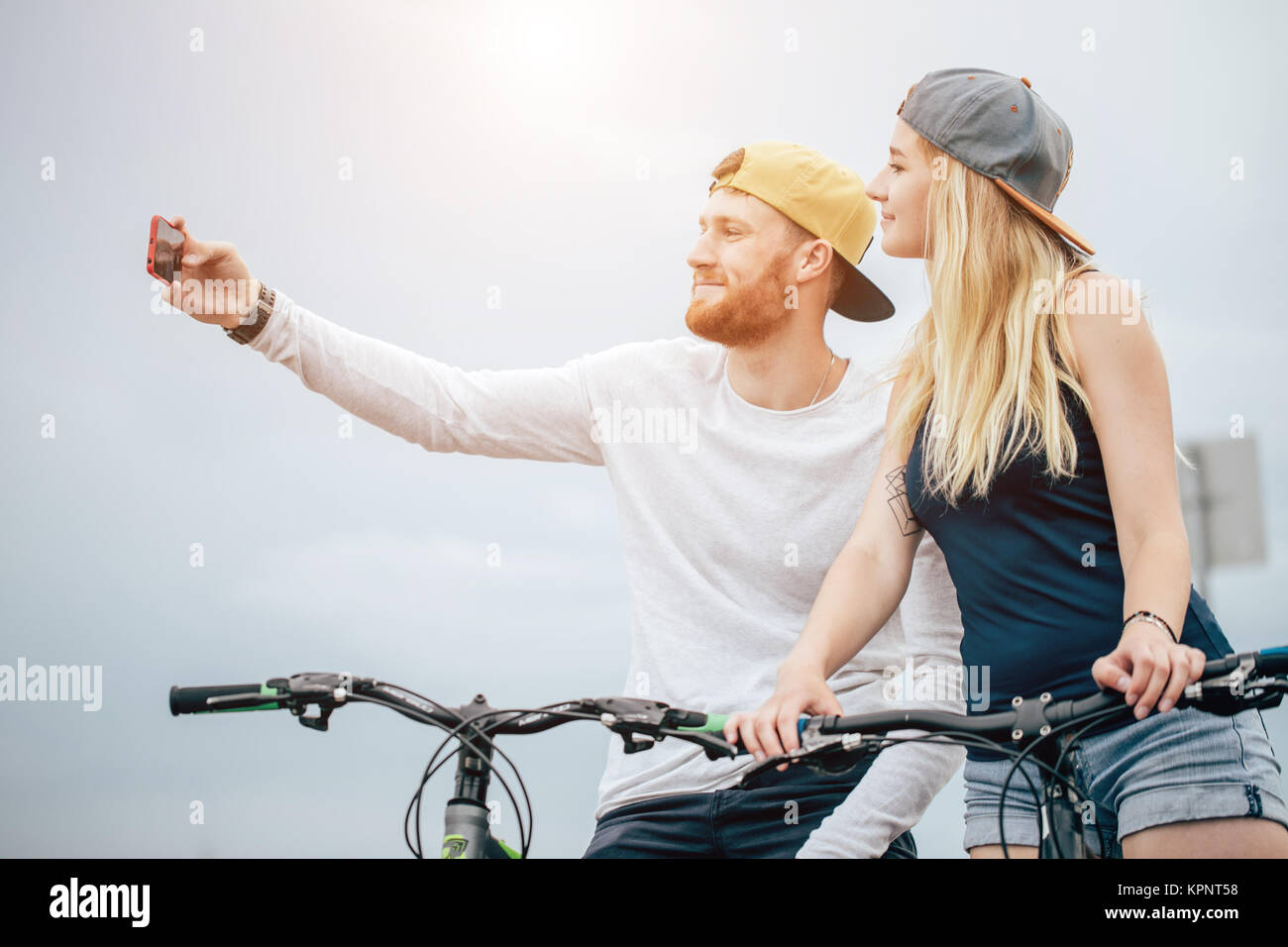 Coppia felice con la bicicletta prendendo selfie all'aperto Foto Stock