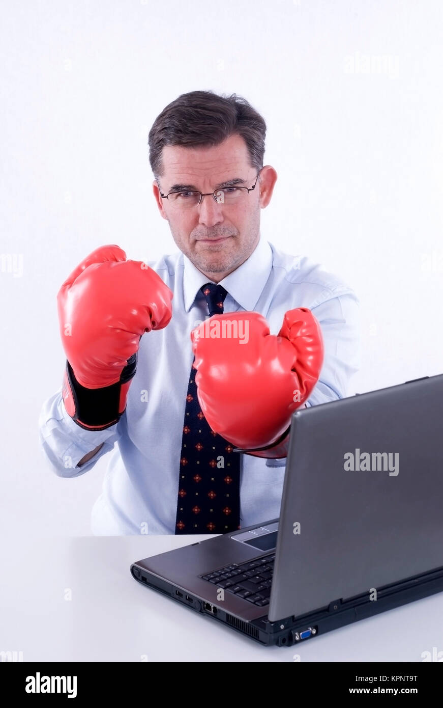 Modello di rilascio , Geschaeftsmann, 50+, mit Boxhandschuhen am Arbeitsplatz - business boxer Foto Stock