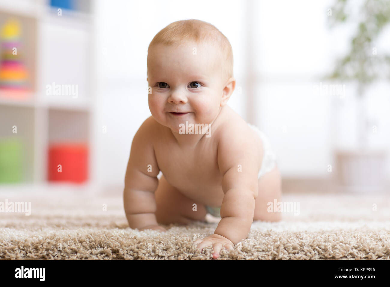 Funny baby boy strisciare sul pavimento a casa Foto Stock
