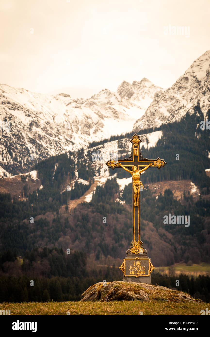 Croce cristiana dorata con catena montuosa sullo sfondo Foto Stock