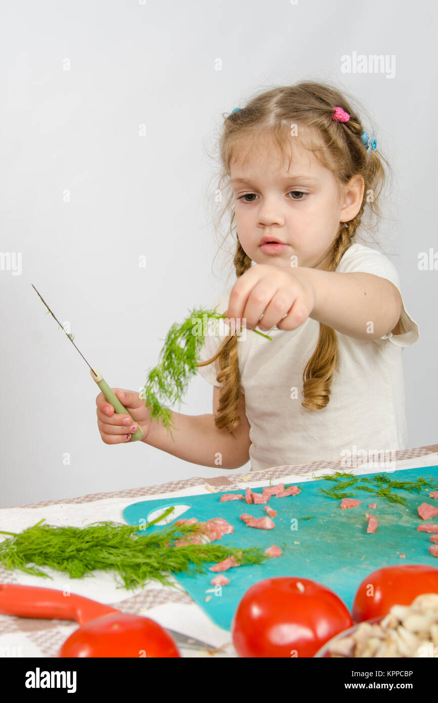 Poco oltre sei anni vecchia ragazza guardando il rametto di prezzemolo sta tenendo in mano Foto Stock