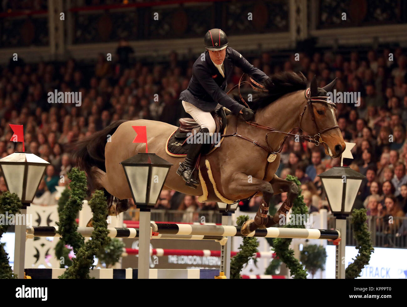 La Gran Bretagna è Michael Whitaker in sella il JB's Hot Stuff compete di Martin Collins imprese albero di Natale picchetti durante il giorno cinque del London International Horse Show a Olympia di Londra. Foto Stock