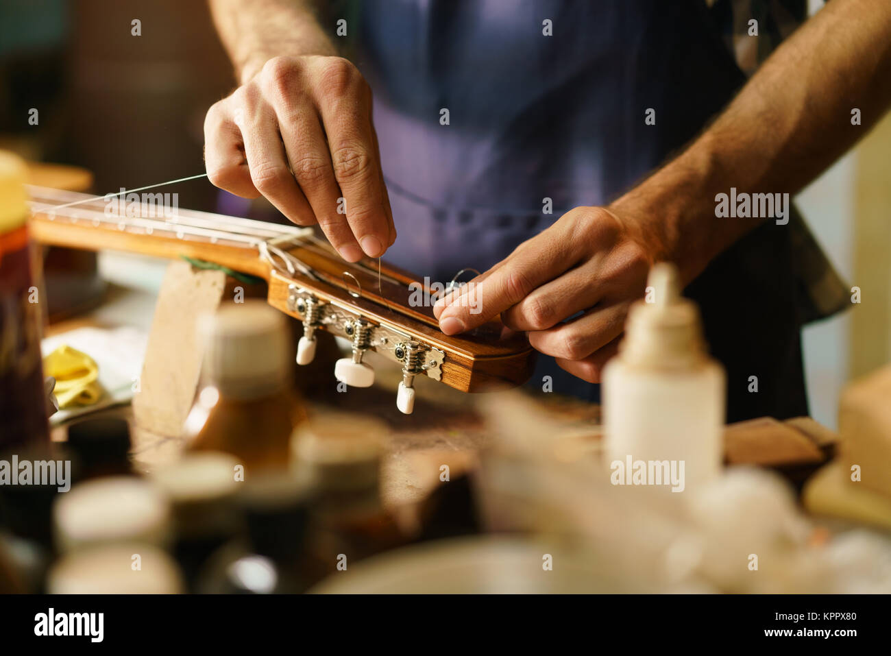 Artigiano liutaio che fissa uno strumento a corda Sostituzione Cavo chitarra Foto Stock