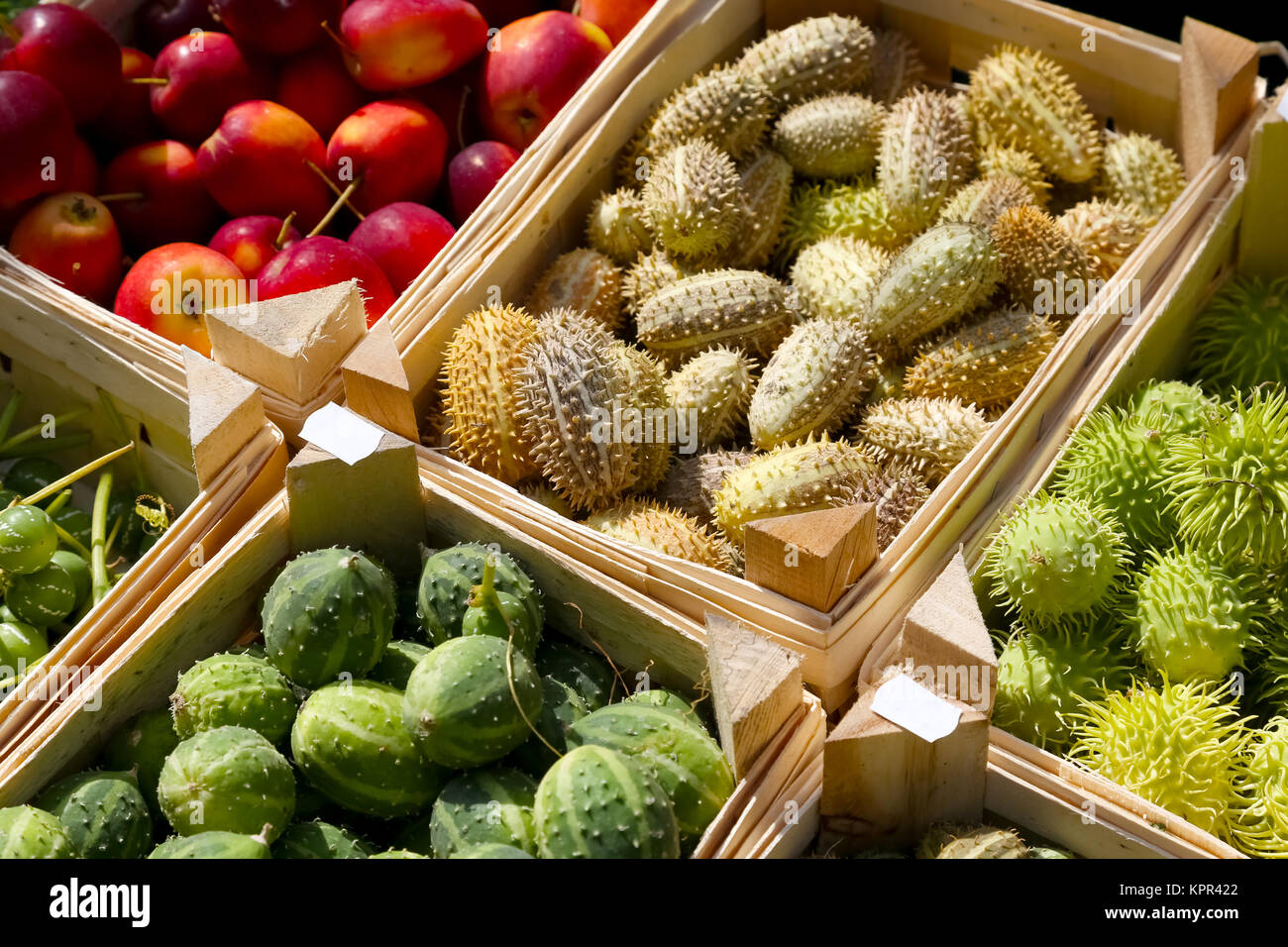 Frutta tropicale e le mele rosse sono collocati separatamente in contenitori di legno. Foto Stock