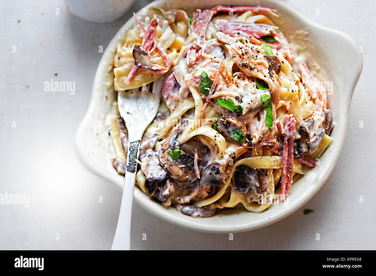 Tagliatelle prosciutto fungo. La pasta in salsa alla panna con prosciutto affumicato e i funghi porcini arrosto Foto Stock