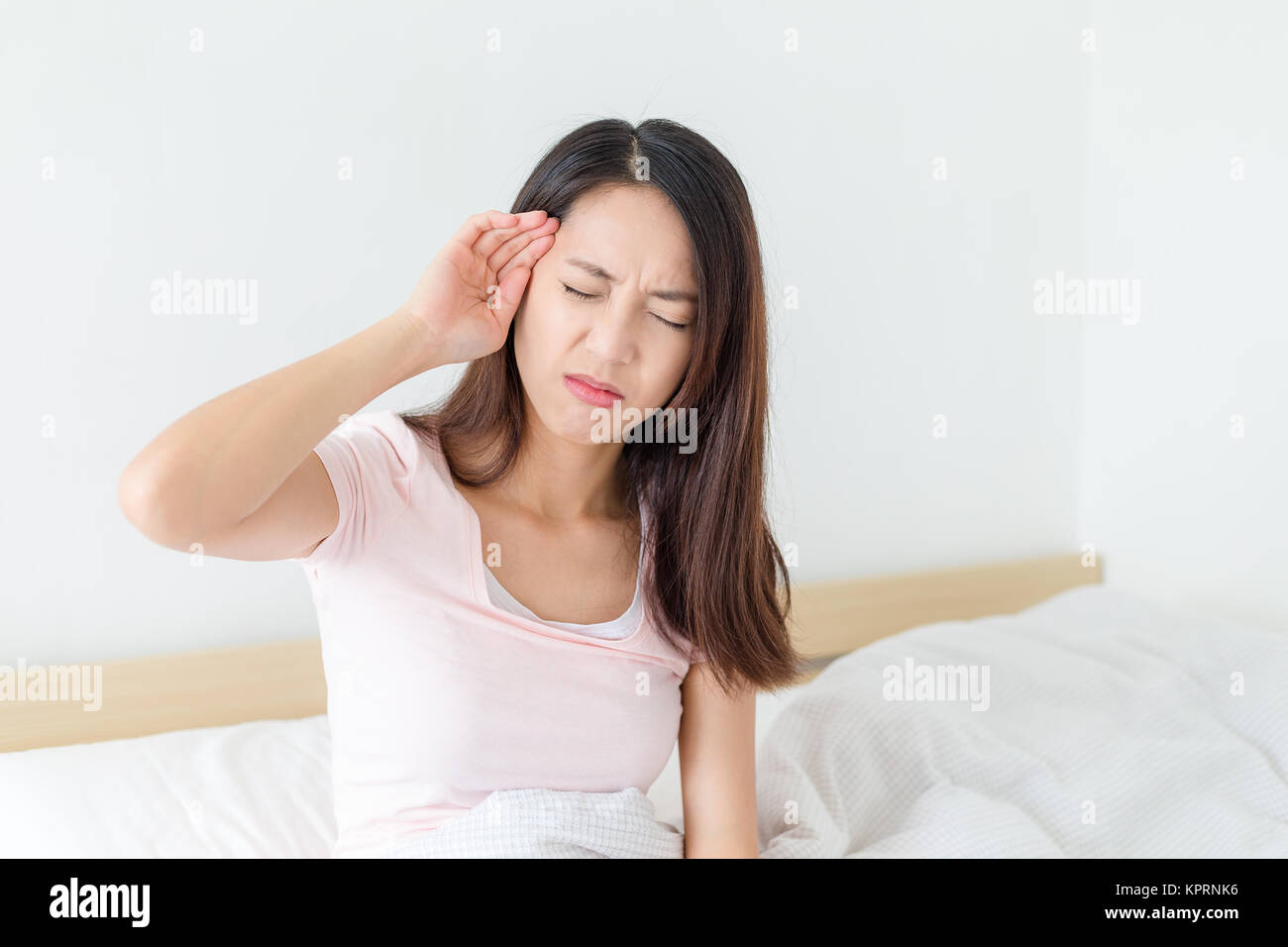 Donna con mal di testa seduto sul suo letto Foto Stock