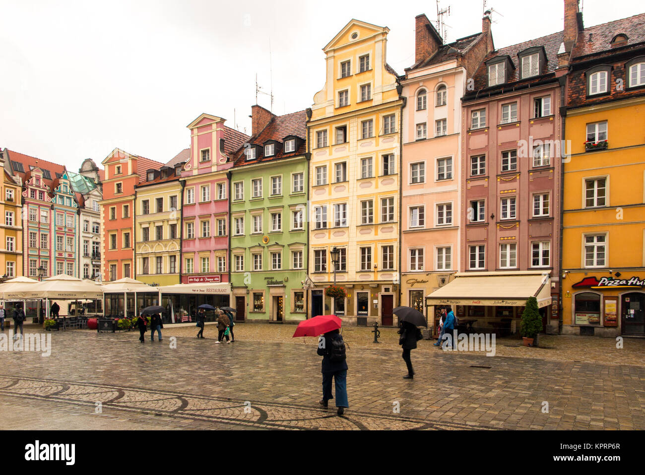 La gente camminare sotto la pioggia sotto vivacemente colorato ombrelloni / ombrelloni in piazza del mercato nella città polacca di Wroclaw Polonia Foto Stock