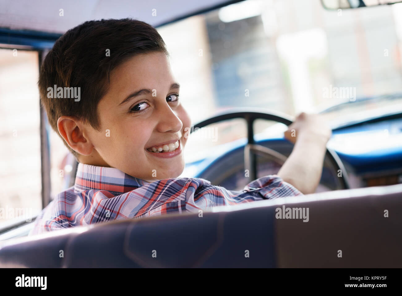 Ritratto bambino tenuto lezione di guida nella vecchia auto sorridente Foto Stock