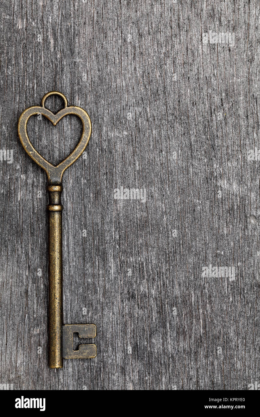 A forma di cuore chiave vintage su grunge sfondo di legno Foto Stock