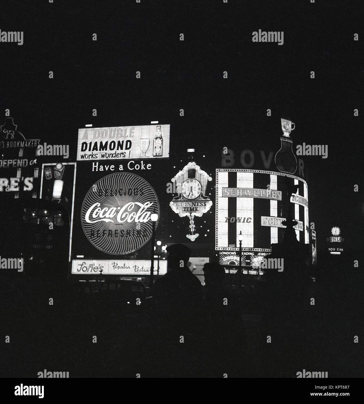 Anni sessanta, foto storiche che mostrano segni di pubblicità e slogan promozionale illuminata di notte a Piccadilly Circus nel West End di Londra, Inghilterra, Regno Unito. Foto Stock
