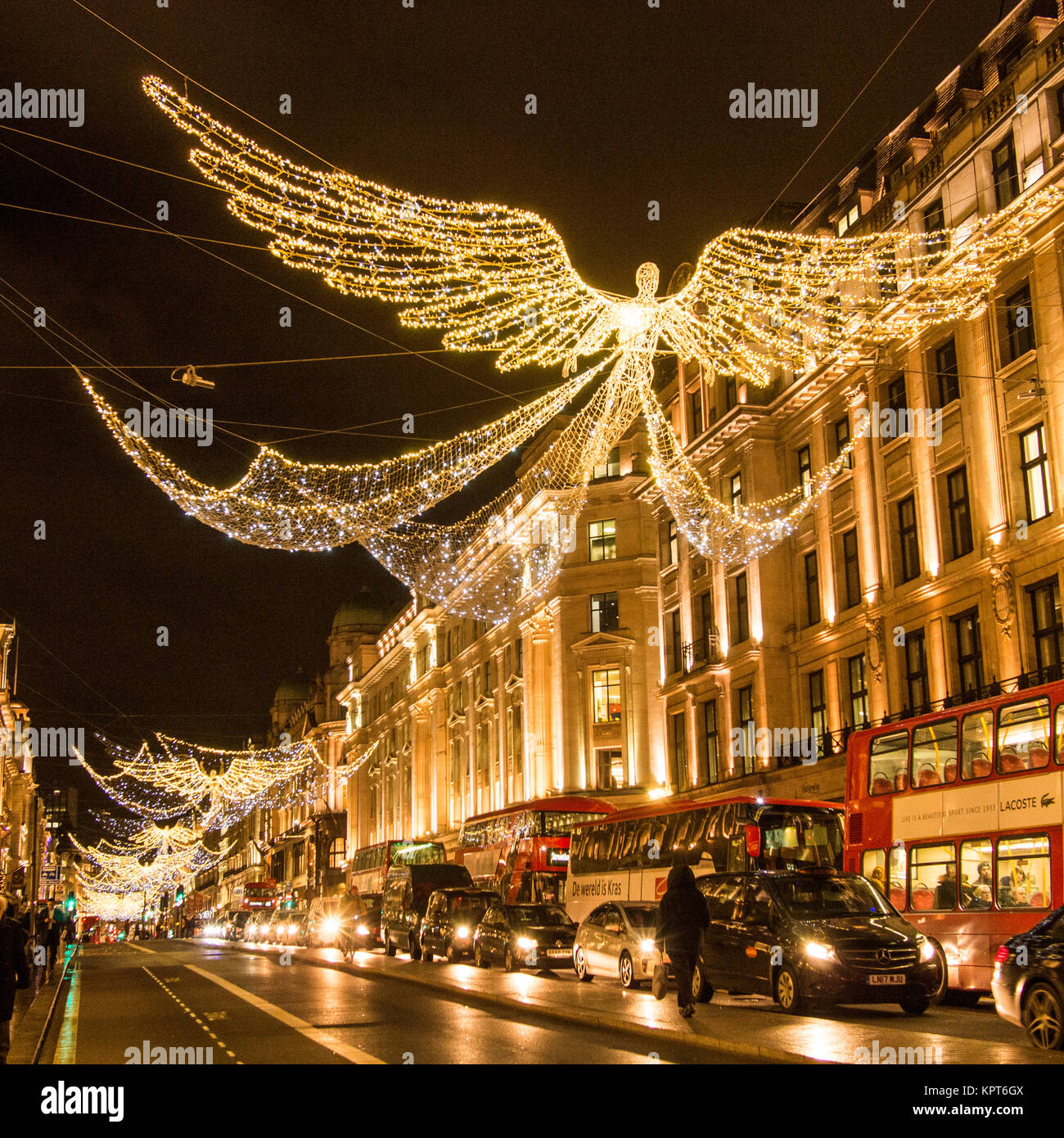 Le luci dell'auto riflettono il marciapiede sotto i festosi 'Angels' di Regent Street, Londra, Inghilterra Foto Stock
