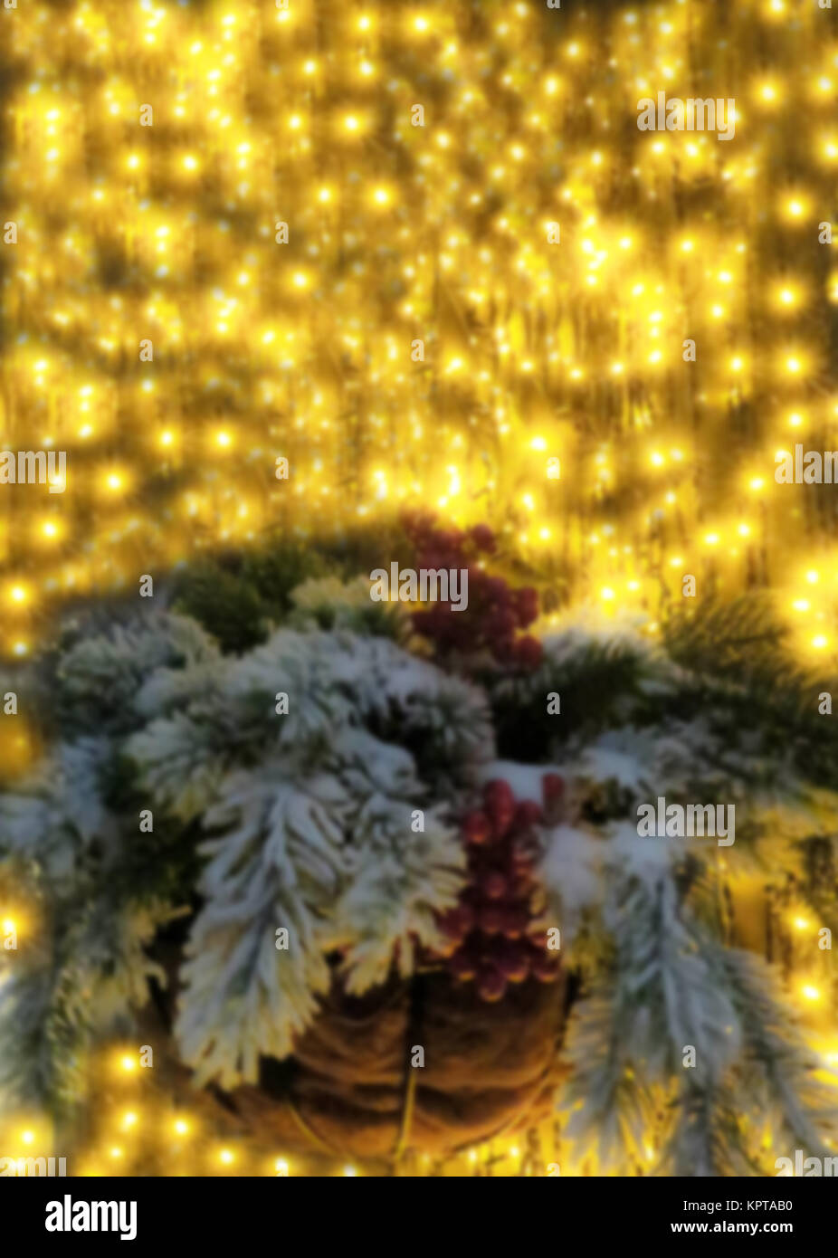 Le decorazioni di Natale cesto con bacche e coperto di neve e rami di abete contro lo sfondo di luci di strada in sfocatura morbida Foto Stock