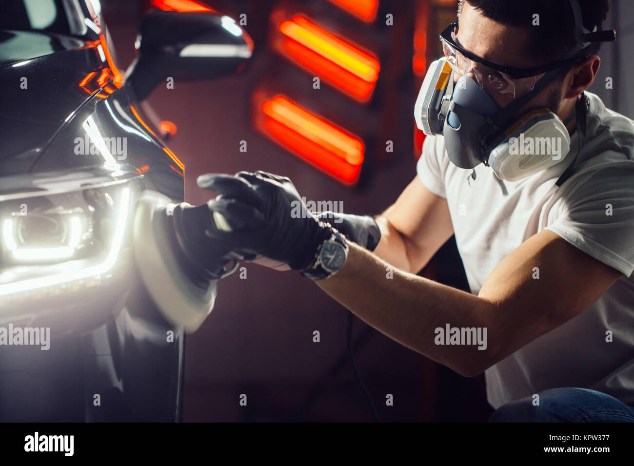 Dettagli auto - uomo con lucidatrice orbitale nel negozio di riparazioni auto. Messa a fuoco selettiva. Foto Stock