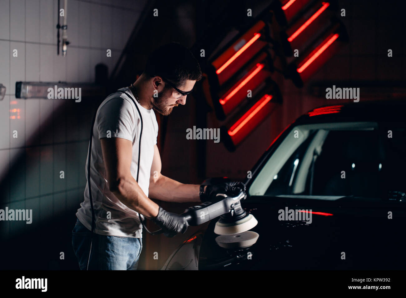 Dettagli auto - uomo con lucidatrice orbitale nel negozio di riparazioni auto. Messa a fuoco selettiva. Foto Stock