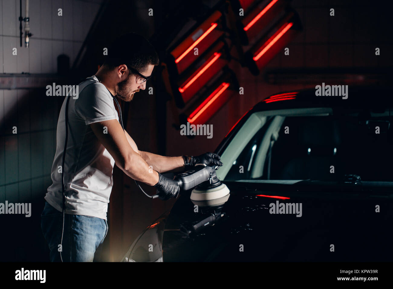 Dettagli auto - uomo con lucidatrice orbitale nel negozio di riparazioni auto. Messa a fuoco selettiva. Foto Stock