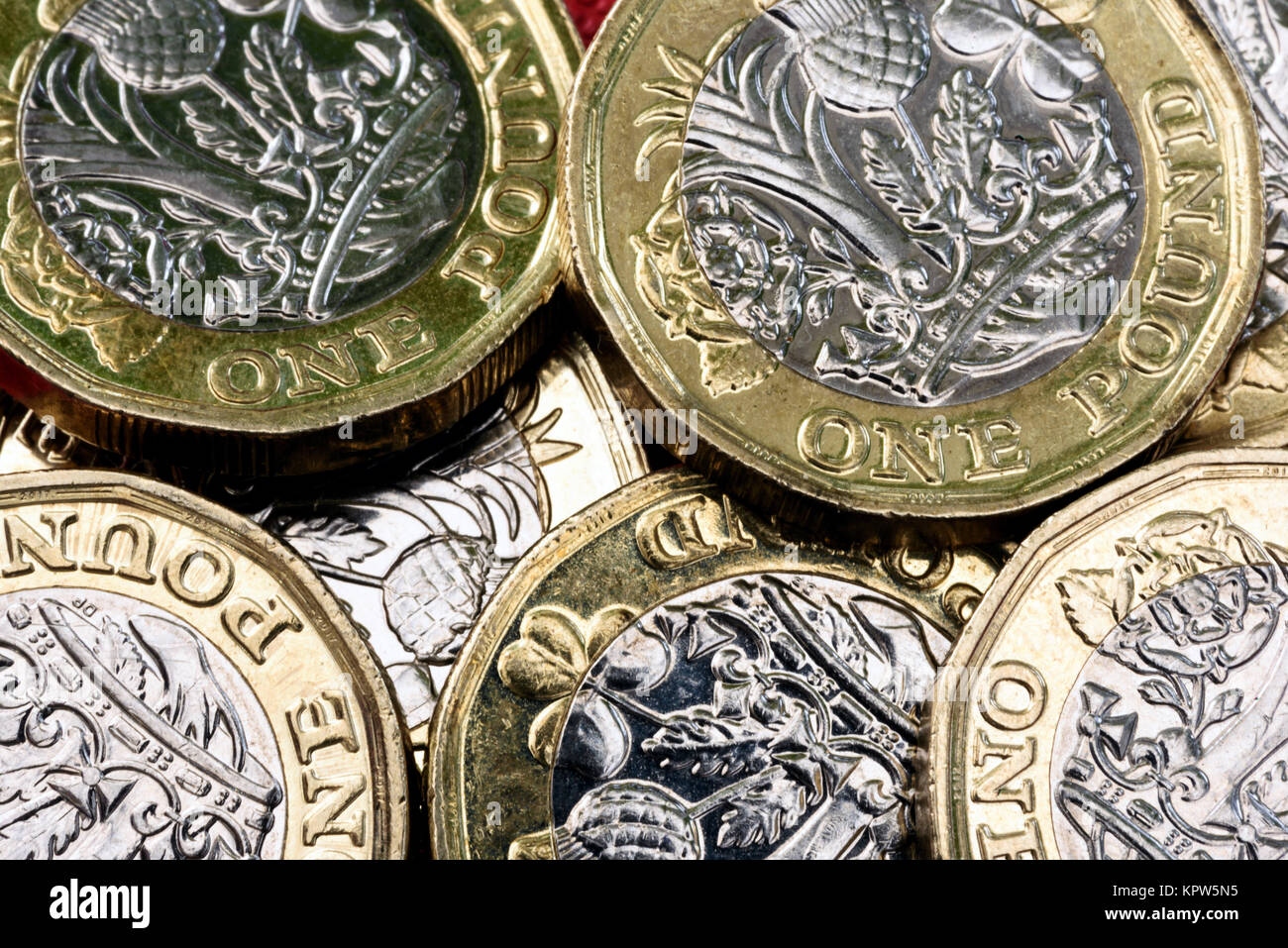 Nuovo lucido sterlina britannica valuta Moneta di argento e oro su sfondo rosso. Le monete sono progettati per fermare la contraffazione di denaro in inglese Foto Stock