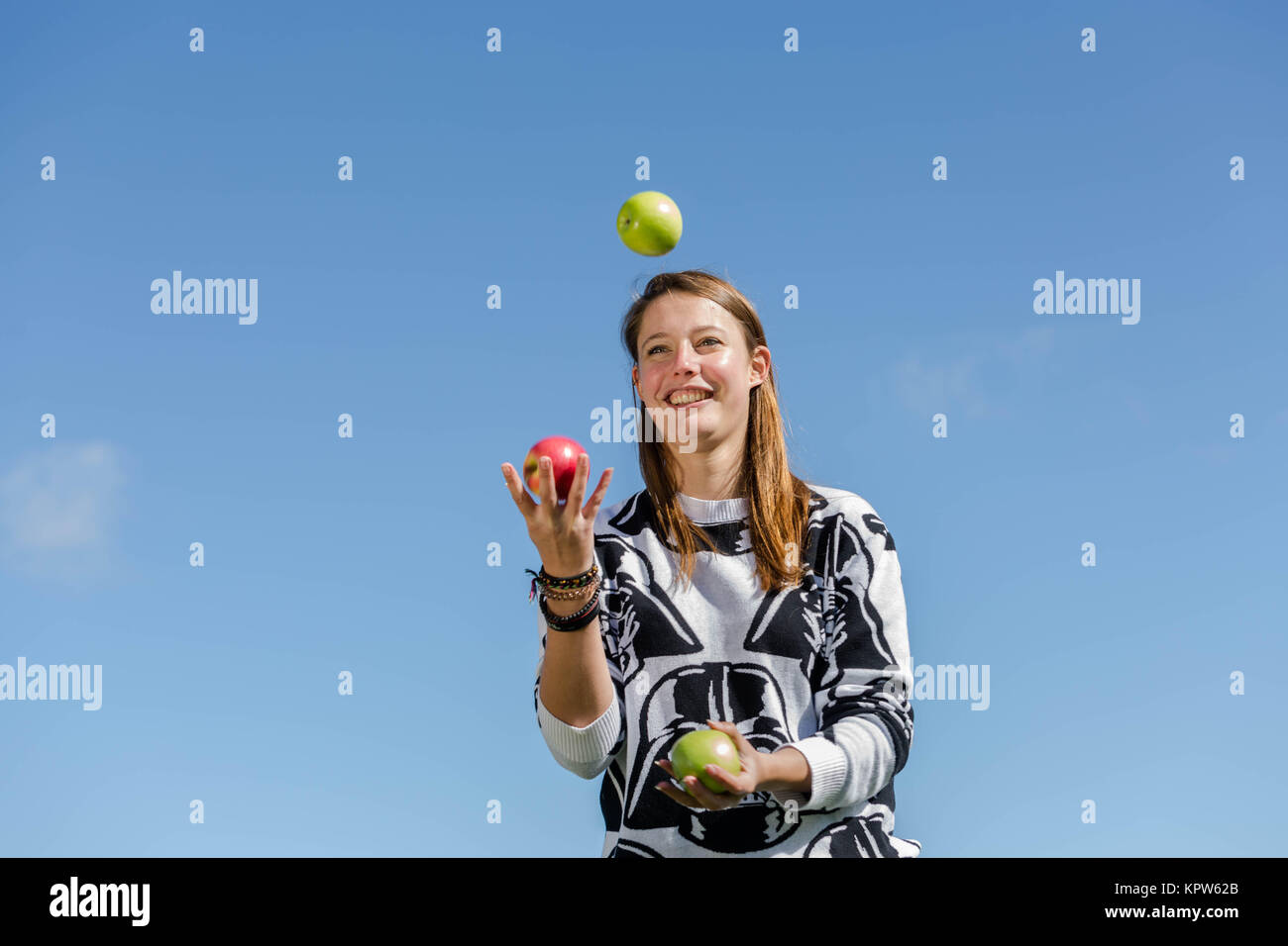 Eine junge Frau jongliert mit frischen und gesunden Äpfeln Foto Stock