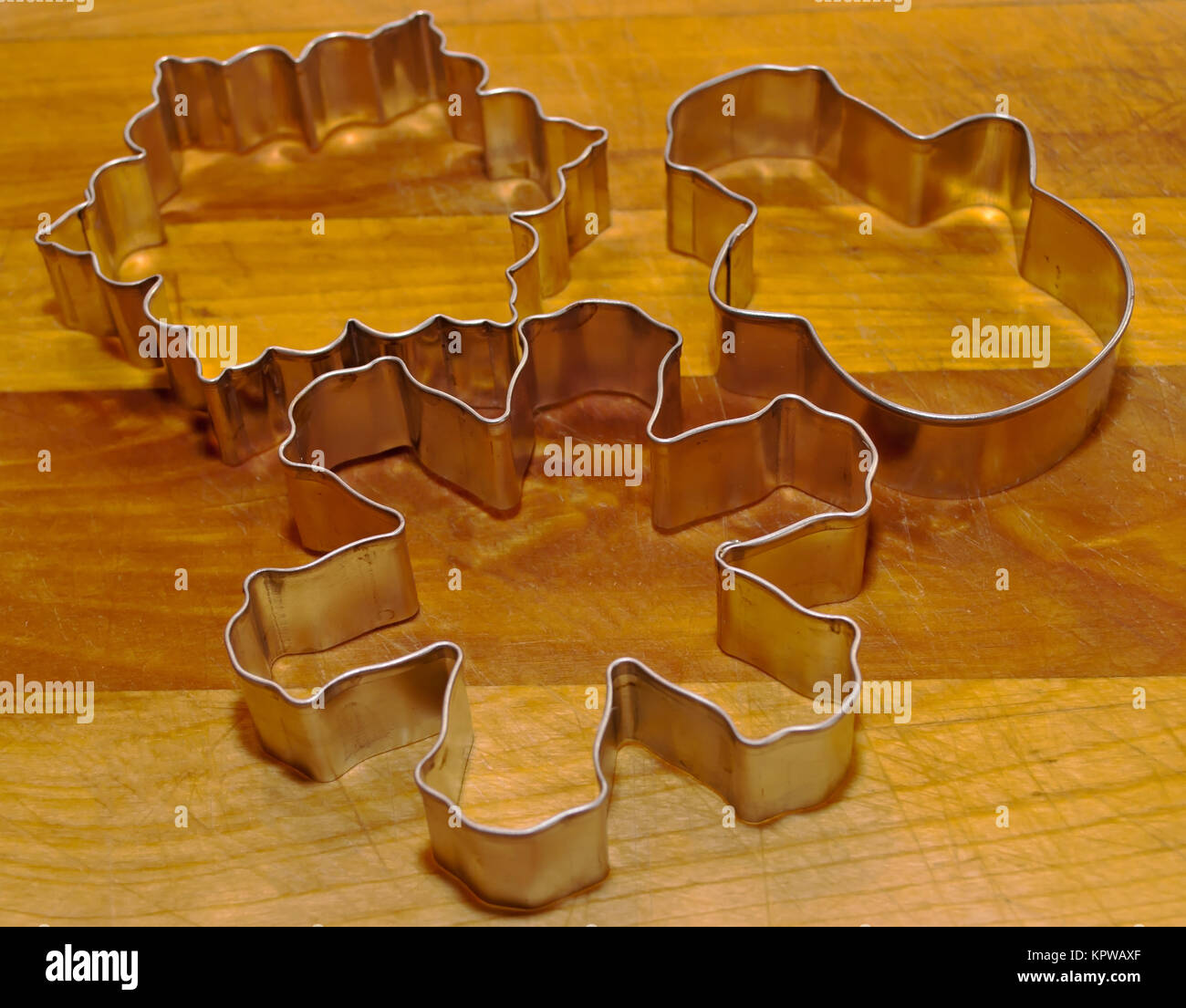 Tre Natale cookie cutters su un tagliere di legno Foto Stock