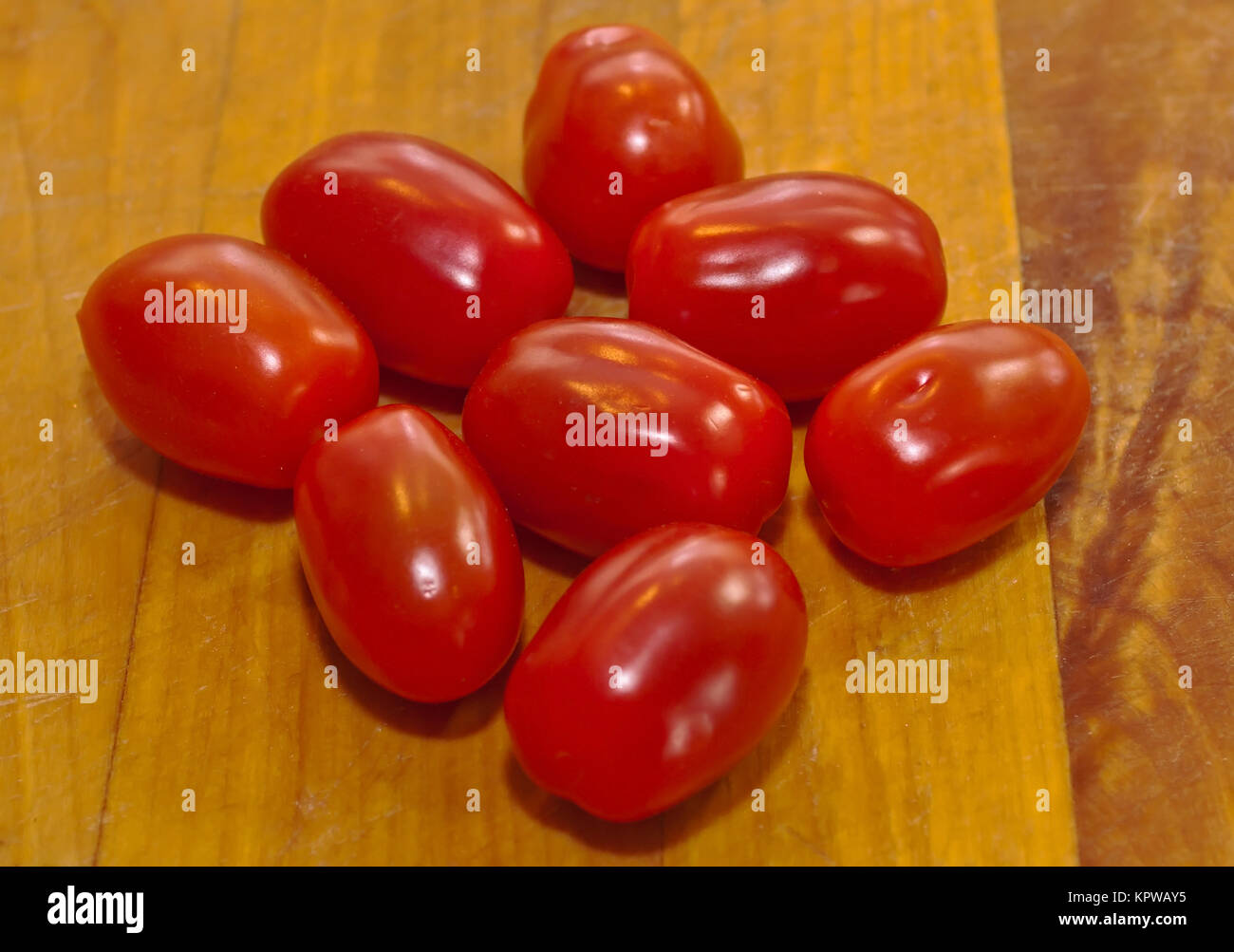 Otto piccoli pomodori ciliegia su una tavola di legno Foto Stock