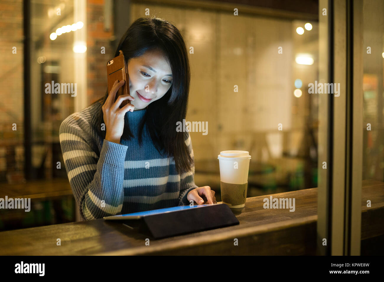 La donna parlare al cellulare e uso del tablet a tazza da caffè Foto Stock