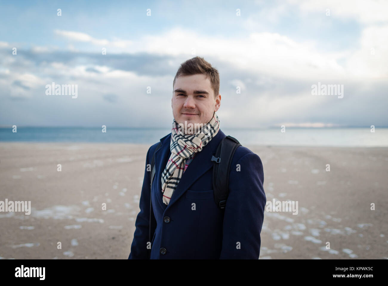 Bella giovane uomo in vestiti eleganti sulla spiaggia invernale in NYC in piedi e guardando la fotocamera. Una persona. Stagione invernale. La spiaggia di Brighton Foto Stock