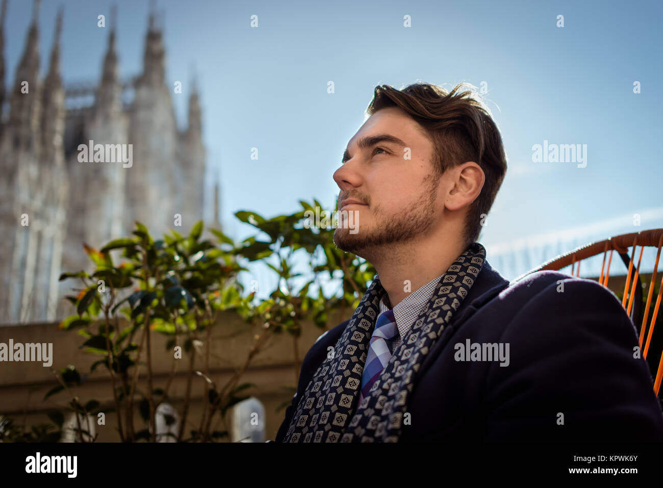 Giovane ed elegante uomo seduto sulla sedia in cafe a terrazza in inverno bella giornata di sole a Milano Foto Stock