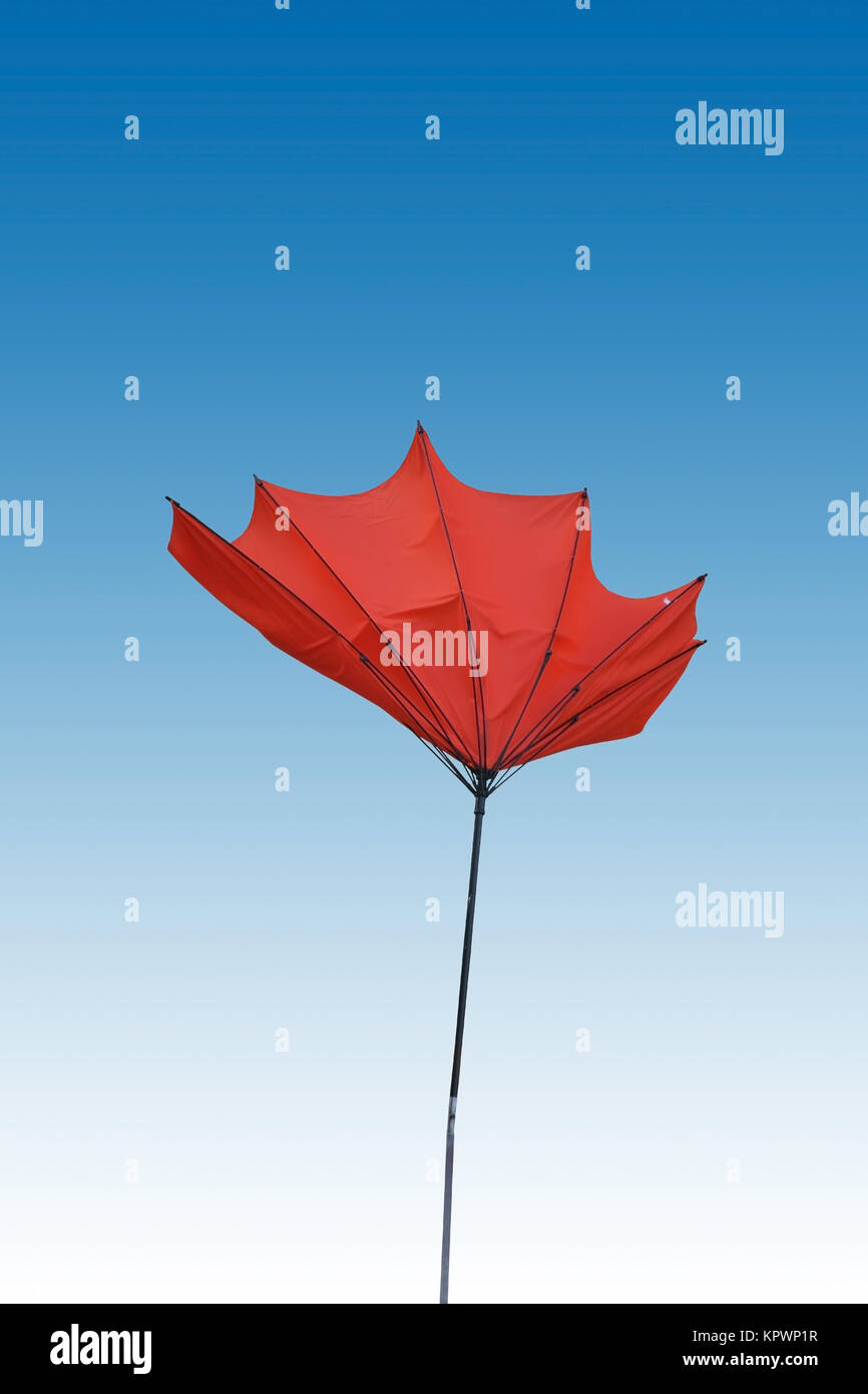 Ein von Wind umgeklappter und isolierter roter ombrellone. Foto Stock