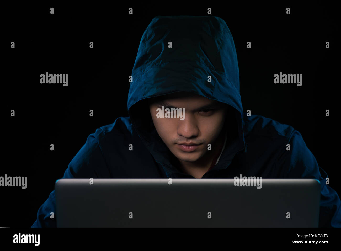 Hacker in una felpa con cappuccio scuro seduto davanti a un notebook. Calcolatore attacco sulla privacy Foto Stock