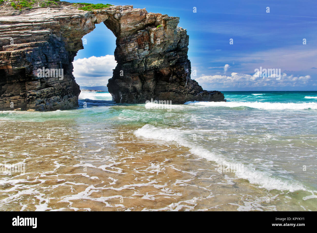 La roccia a forma di arco sulla spiaggia dell'oceano. Spagna settentrionale, Praia de Augas Santas, soleggiata giornata estiva Foto Stock