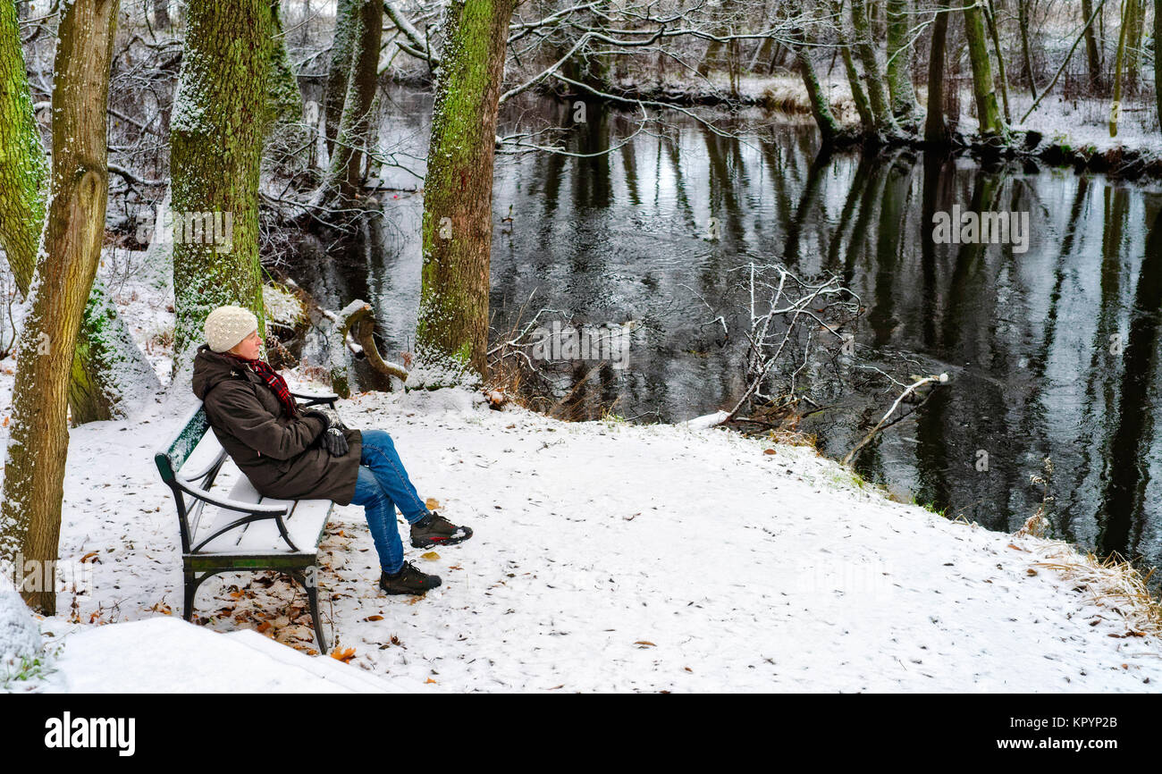 Donna seduta su una panchina in inverno Foto Stock