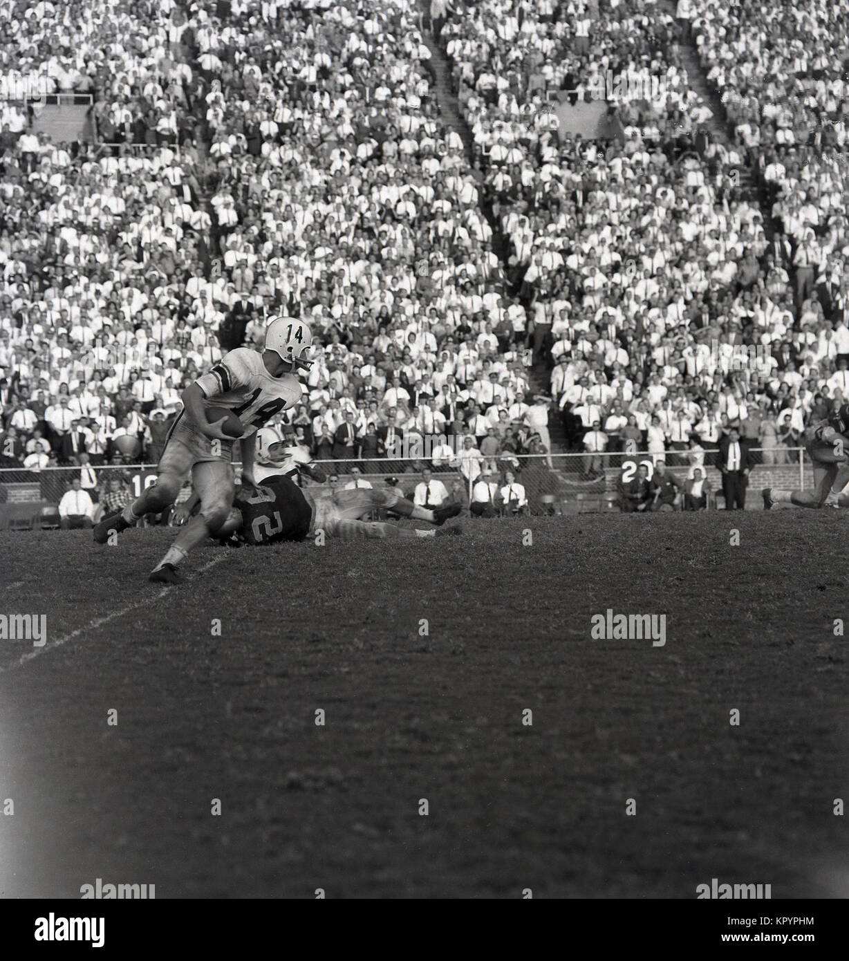 Anni sessanta, foto storiche che mostra una grande folla puntato guardando un entusiasmante gioco di football americano, STATI UNITI D'AMERICA. Foto Stock