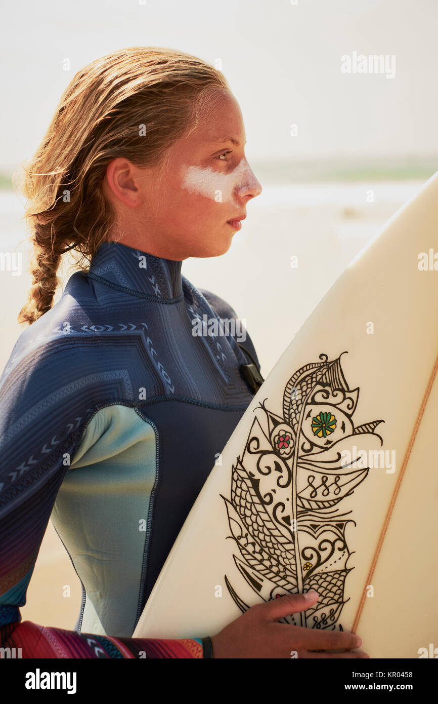 Un ritratto di stile di vita di una ragazza adolescente surfer con protezione dai raggi UV e una tavola da surf Foto Stock