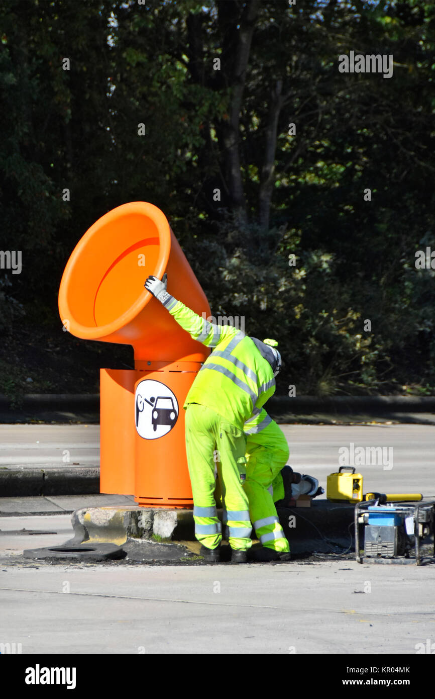 Operai installazione orange alta livello cestini per uso da parte di entrambi i camion e i conducenti di auto uscire Lymm M6 Motorway Services nel Cheshire England Regno Unito Foto Stock