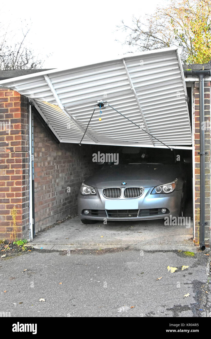 Una di una fila di quattro garage per auto nella strada dietro i negozi danno a up & oltre porta BMW auto interno chiaro come si è verificato il danno Essex England Regno Unito Foto Stock