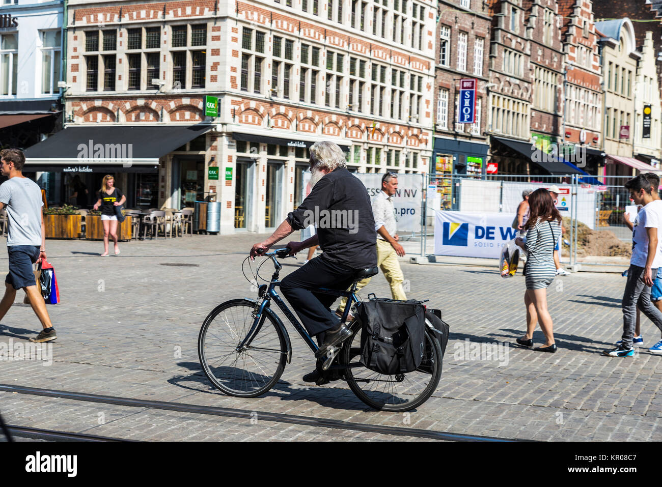 Ghent, Belgio - 29 agosto 2017: Senior uomo vestito di nero sulla circolazione in bicicletta e gente che passeggia in un antico centro storico della città medievale Foto Stock