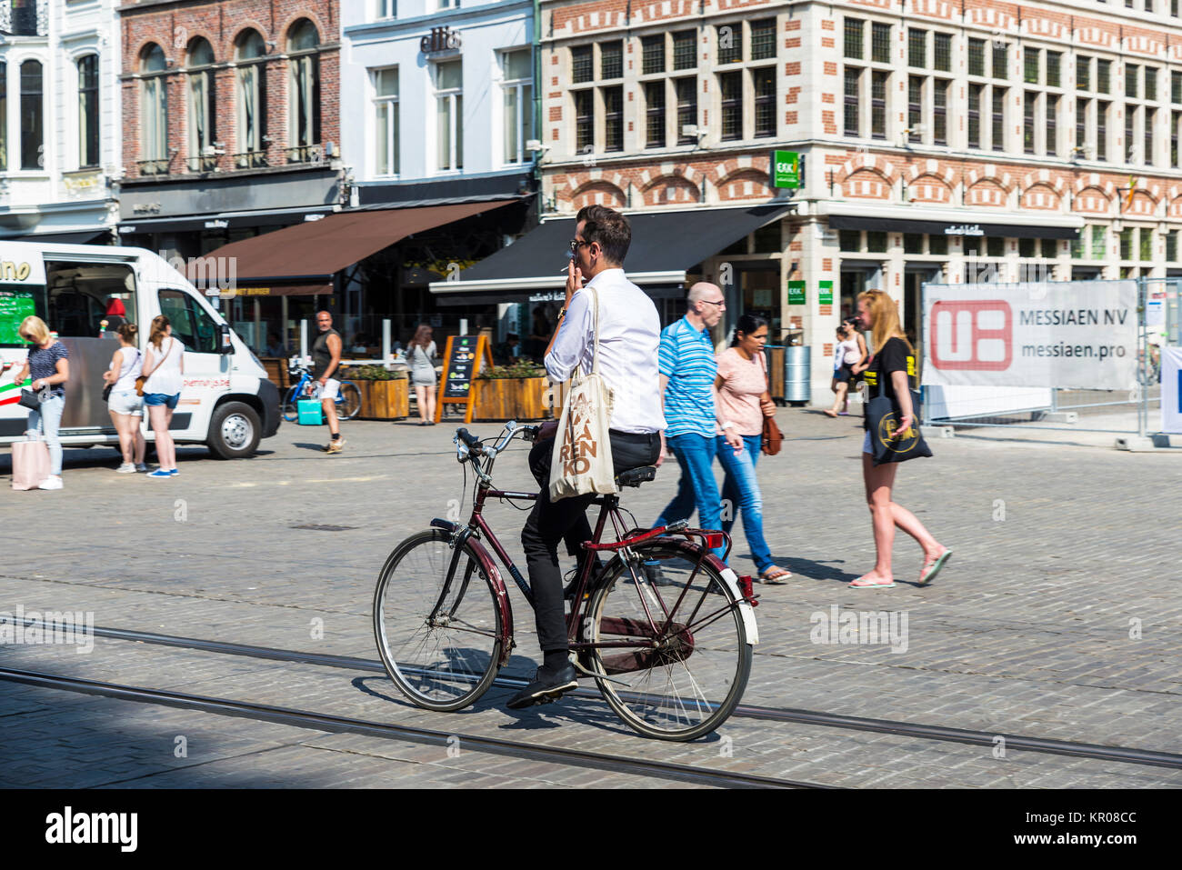 Ghent, Belgio - 29 agosto 2017: il giovane uomo del fumo sulla circolazione in bicicletta e gente che passeggia in un antico centro storico della città medievale di Gand, Foto Stock