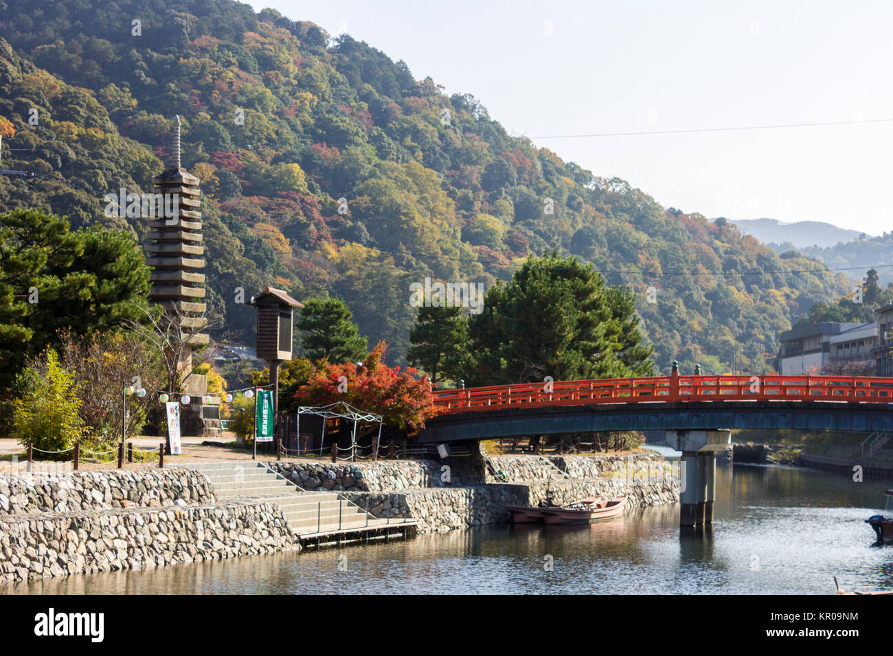 Il tredici piani pagoda in pietra a Uji, Giappone, accanto a un rosso ponte di legno Foto Stock