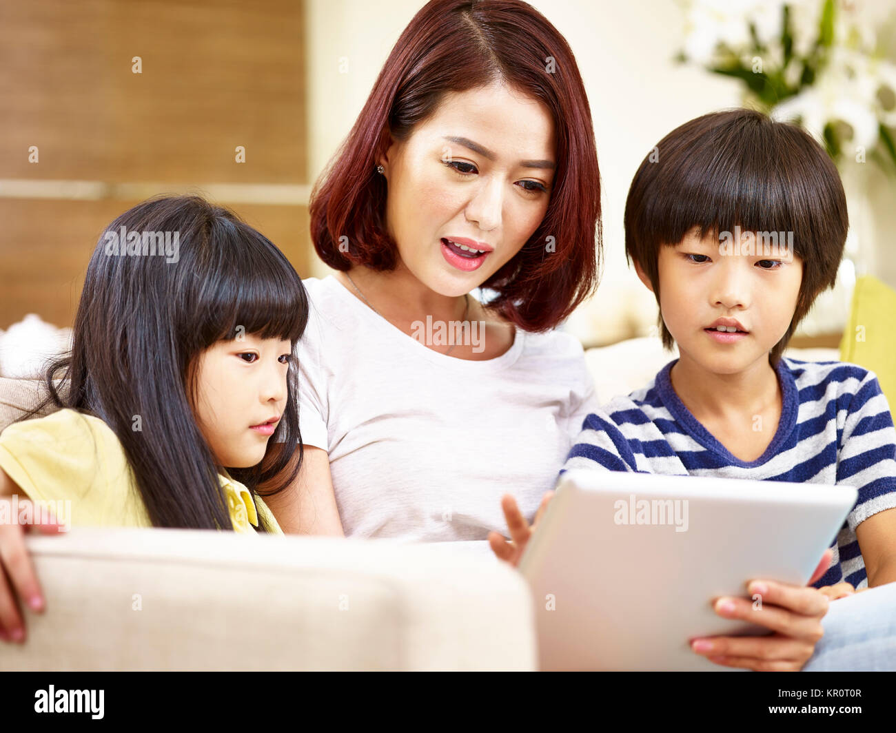 Giovani asiatici madre giocando con tavoletta digitale insieme con il figlio e la figlia. Foto Stock