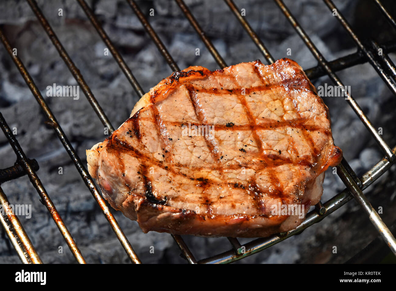 Una bistecca di carne cotti pronti sulla griglia Foto Stock