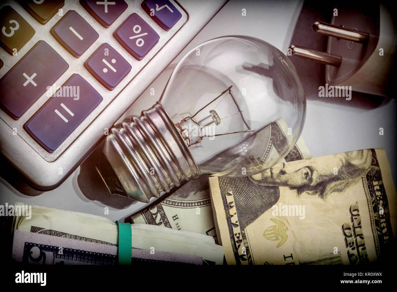 Calcolatrice e denaro accanto a una lampadina, il concetto di risparmio energetico Foto Stock