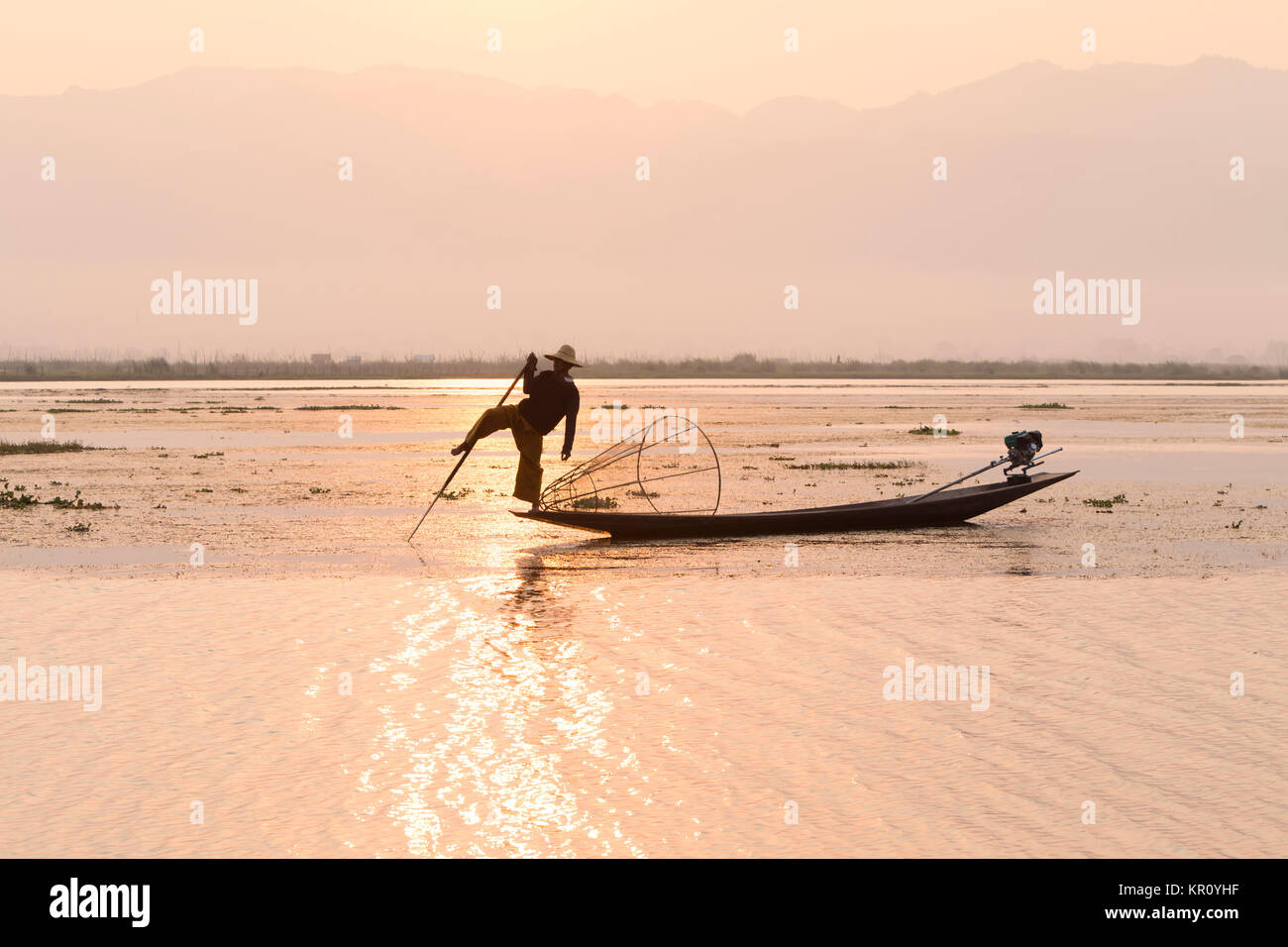 Lago Inle pescatore in piedi su un longtail boat in gamba distintivo atteggiamento di canottaggio utilizzato dal popolo Intha, Lago Inle, Myanmar Foto Stock